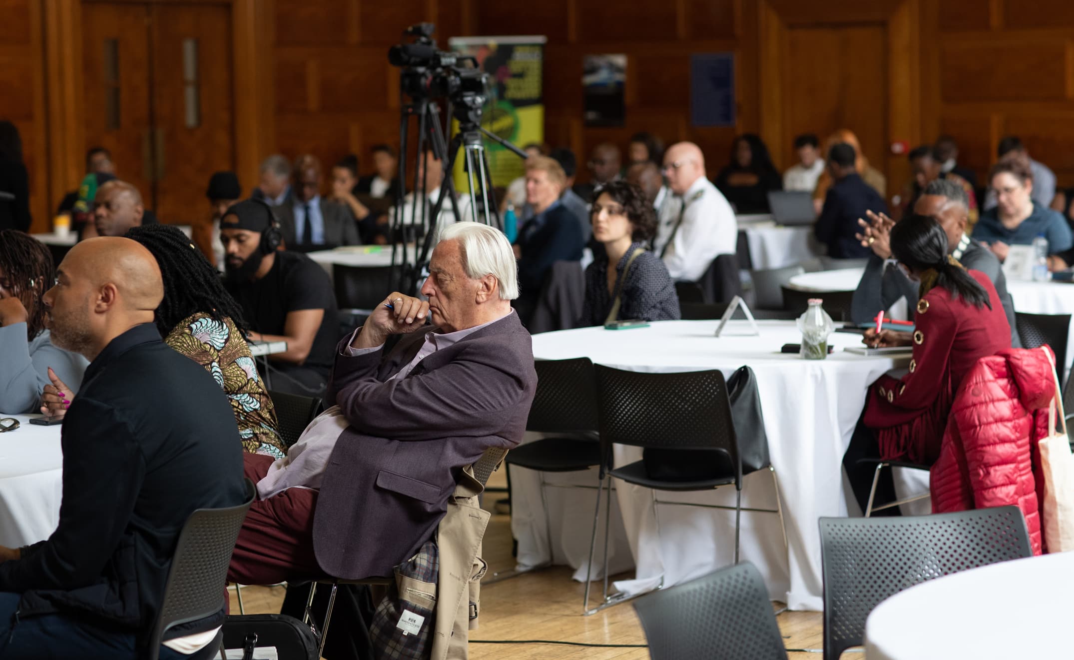 A packed room of delegates listening to an expert panel at an APA conference, with a camera recording the session