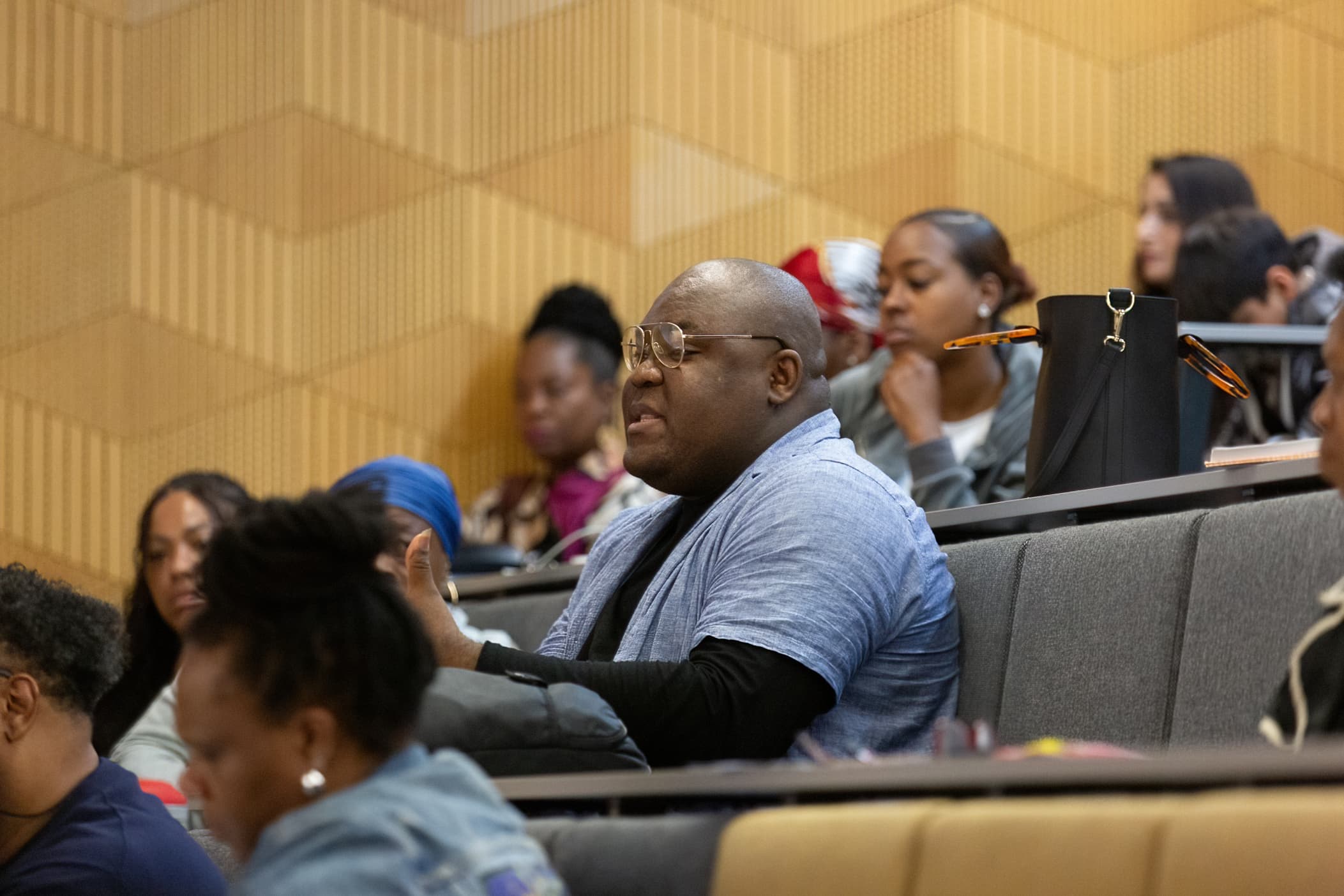 An audience member in glasses speaking from his seat in a lecture theatre at an APA conference