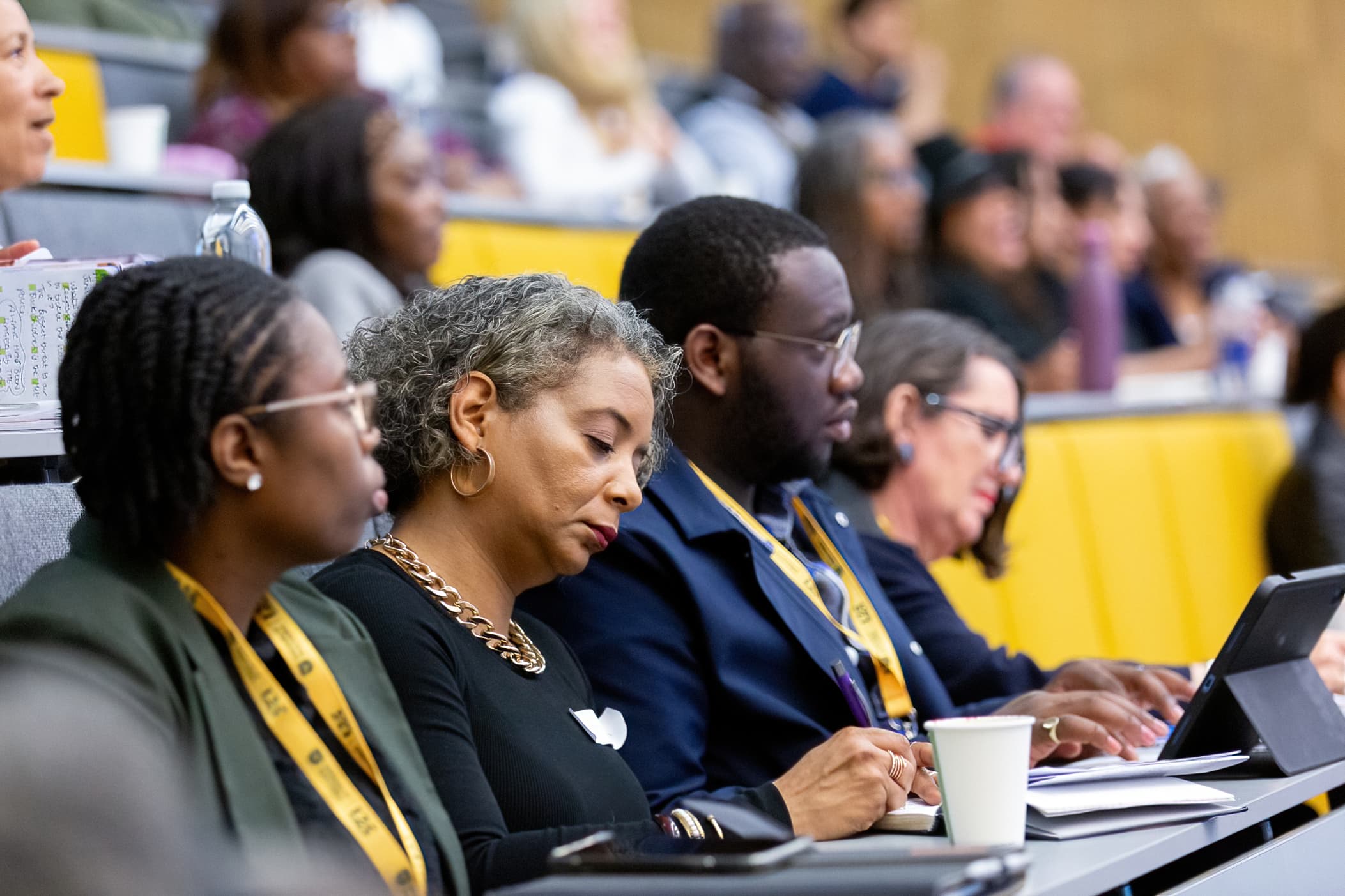 Delegates in a lecture theatre taking notes on paper and a tablet during an APA conference session