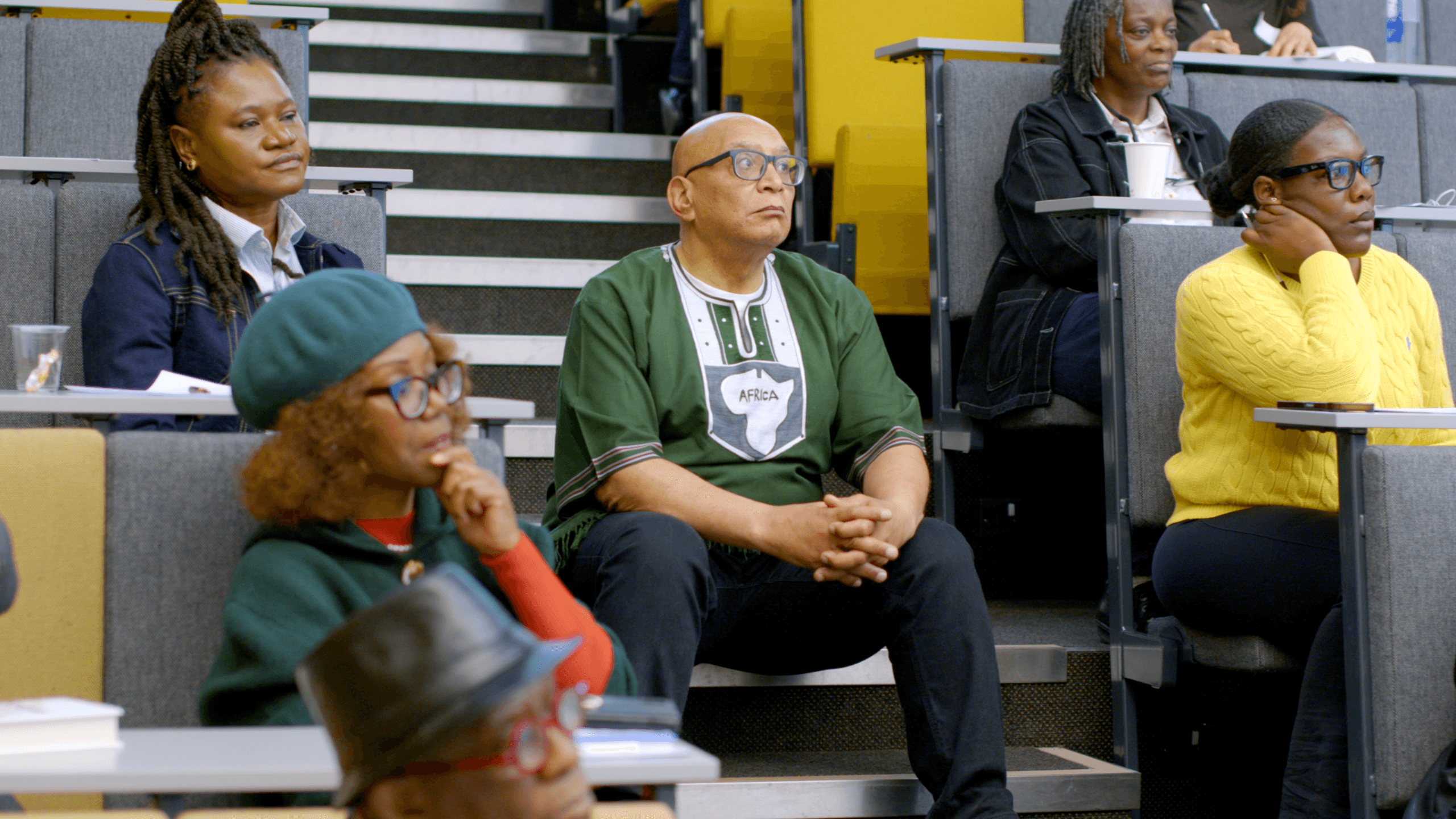 Attendees seated in a tiered lecture theatre, listening attentively